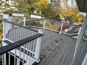 A newly installed outdoor deck with white railings and dark composite decking by Inova Builds in Bloomington, MN.