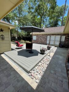 A newly installed outdoor deck and paver patio with decorative landscaping rocks, completed by M7 Remodel & Restoration Inc. in Houston, TX