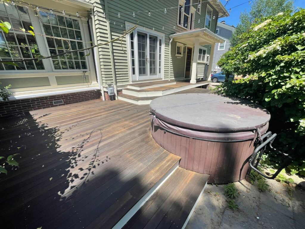 A renovated outdoor wooden deck with a hot tub, showcasing deck maintenance and staining services by Quinonez Painting & Renovations LLC in Providence, RI.