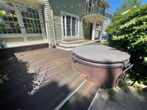 A renovated outdoor wooden deck with a hot tub, showcasing deck maintenance and staining services by Quinonez Painting & Renovations LLC in Providence, RI.
