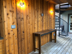 An outdoor deck featuring wood paneling, a custom wooden table, and a spiral staircase by Kaleidoscope Design Build in Houston, TX.