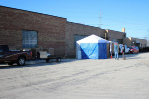 An outdoor e-waste collection event setup by New Earth Computer Recycling in Appleton, WI, with a tent, truck, and trailer.