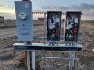 An outdoor electrical service setup with a meter and panels installed in a rural area by Delaney's Electric Inc. in Ault, CO.