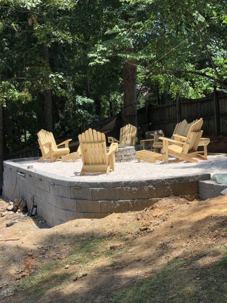 An outdoor fire pit area with wooden chairs and a retaining wall, built by Drip Dry Drainage in Cramerton, NC.