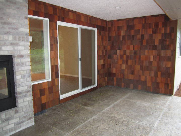 An outdoor covered patio featuring a brick fireplace, cedar shake wall, and sliding door by Qual-i-Tee bilt homes - Steve Johnson in Salem, OR.