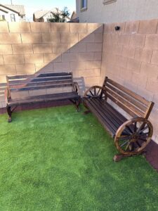 Two dark wooden outdoor benches with wagon wheel designs assembled by Peak Handyman Services in Las Vegas, NV.
