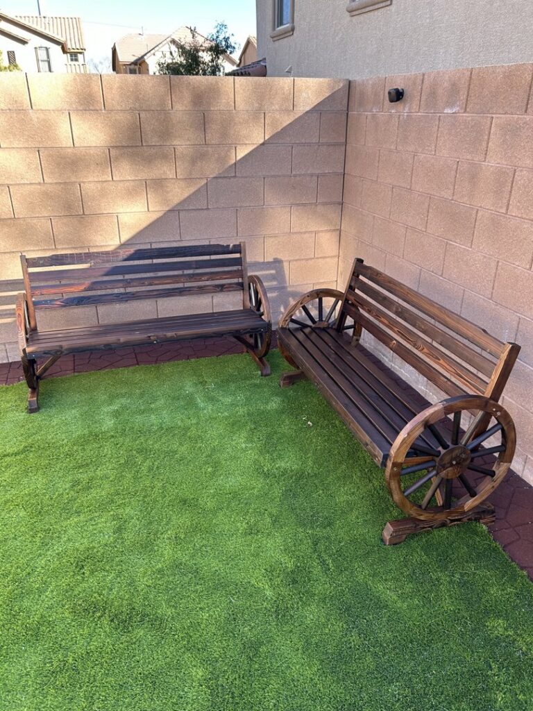 Two dark wooden outdoor benches with wagon wheel designs assembled by Peak Handyman Services in Las Vegas, NV.