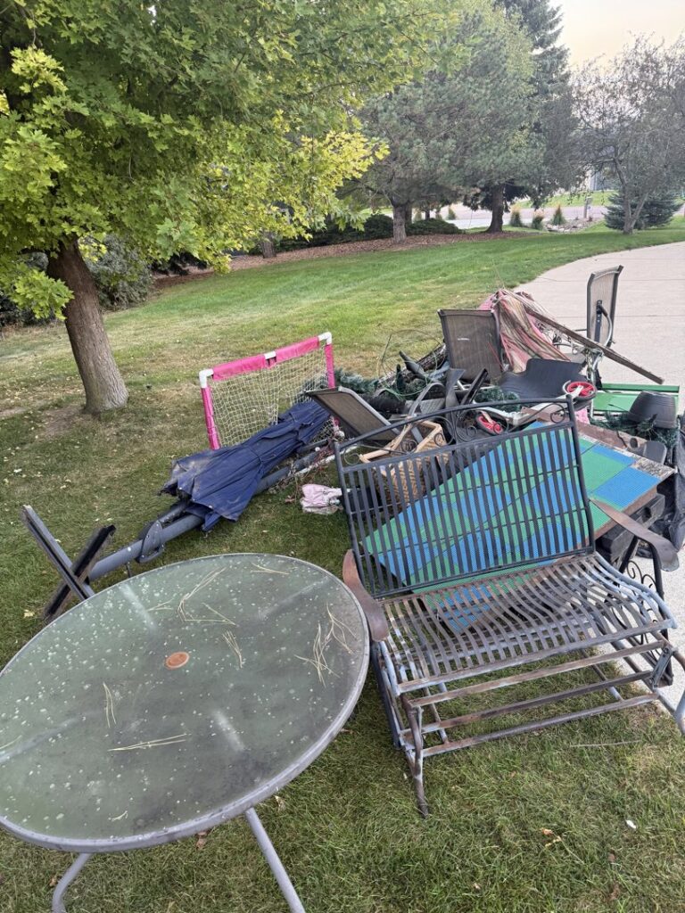 A large pile of old outdoor furniture and miscellaneous junk on a residential lawn, ready for BeeBop's Junk Removal in Sioux Falls, SD.
