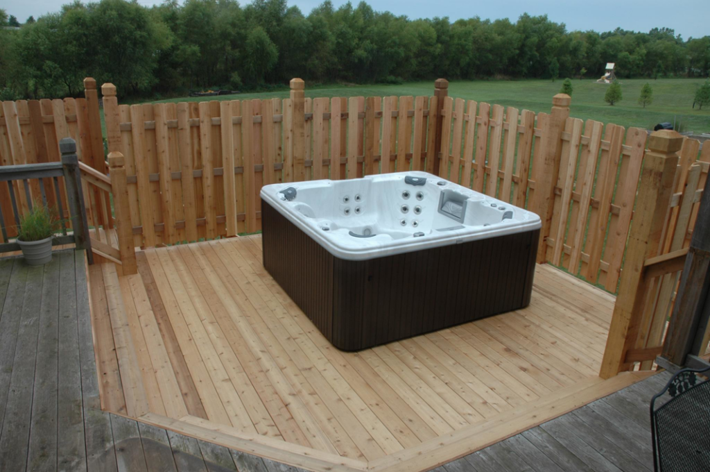 An outdoor hot tub area with a wooden deck and surrounding fence by Holm Remodeling Company in Kansas City, KS.