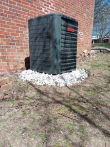 An outdoor residential HVAC unit installed next to a brick wall, a service provided by Pollock HVAC & Electrical in Albany, GA