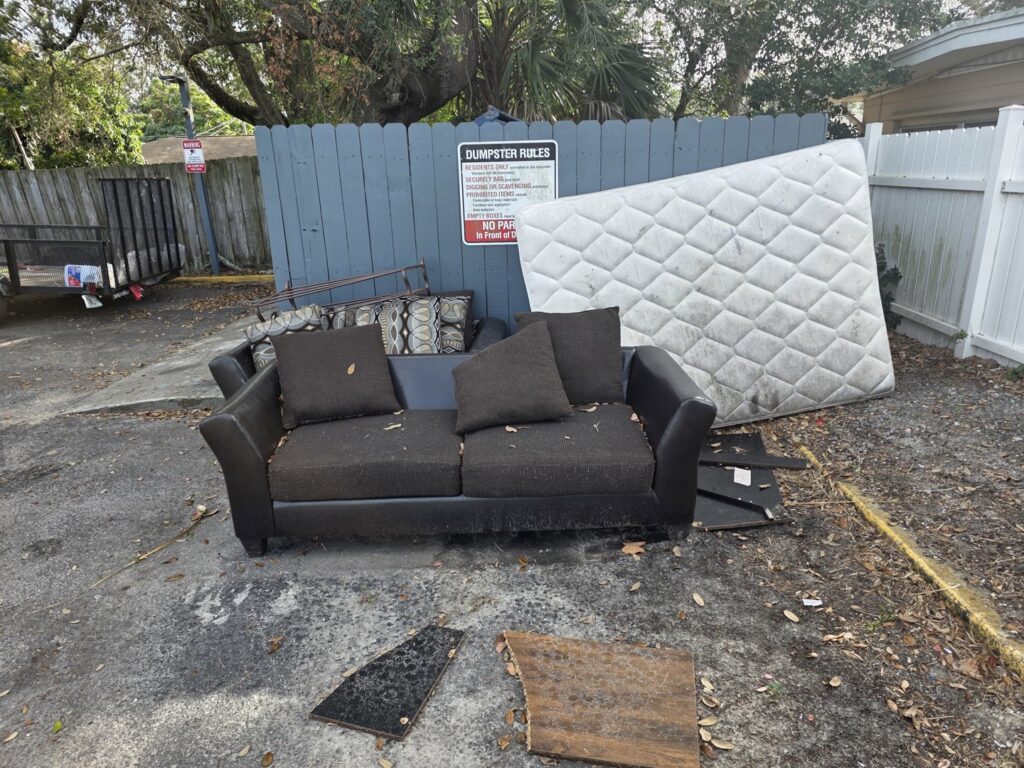 An outdoor pile of junk including a mattress and couch, awaiting removal by Westish Junk Removal LLC in Orlando, FL.