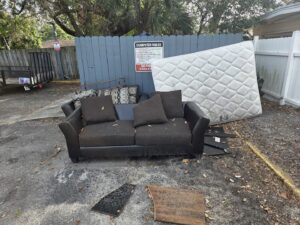 An outdoor pile of junk including a mattress and couch, awaiting removal by Westish Junk Removal LLC in Orlando, FL.