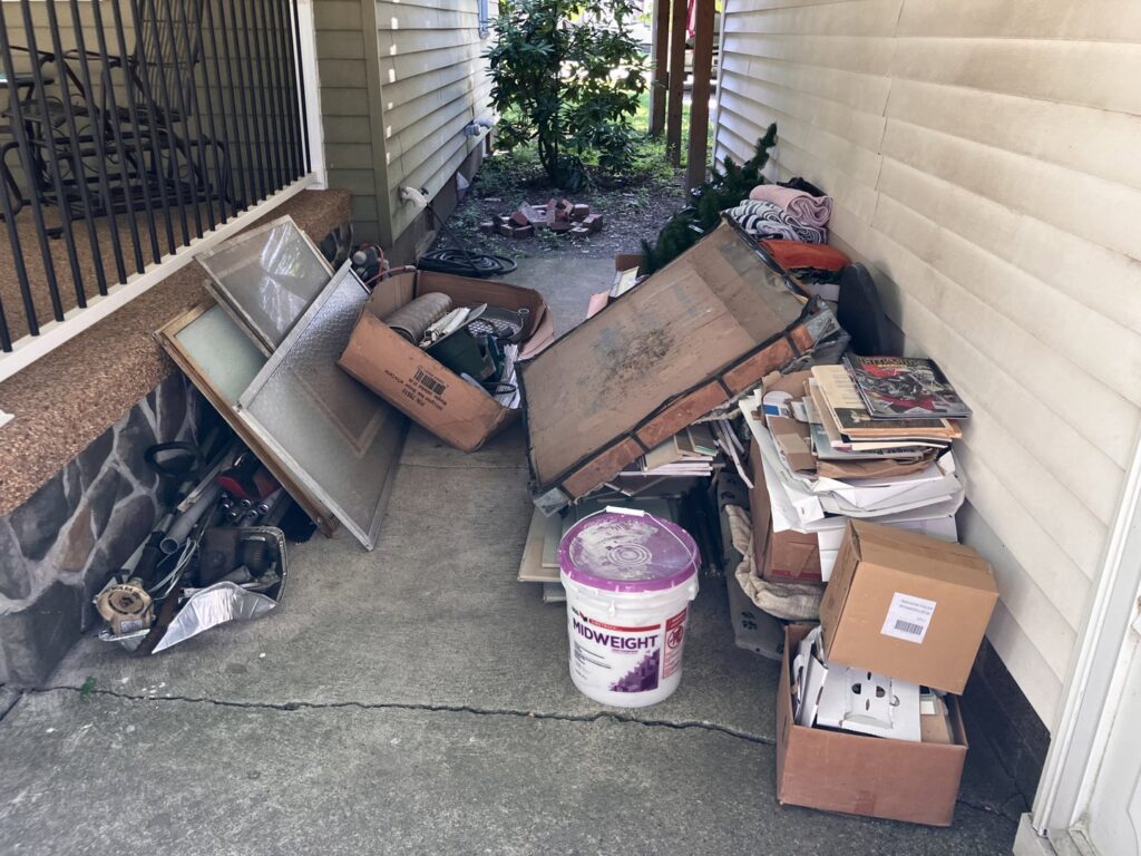 A pile of mixed junk, including windows, bricks, and boxes, on a porch or walkway, ready for removal by HaulPros in Erie, PA.