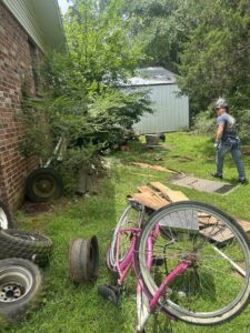 A person working near a large pile of outdoor junk, including tires and a bicycle, for removal by Junk Hawgs Removal and Rentals in Russellville, AR.