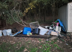 A large pile of outdoor junk, including buckets and plastic items, next to a shed, ready for removal by Junk Hawgs Removal and Rentals in Russellville, AR.