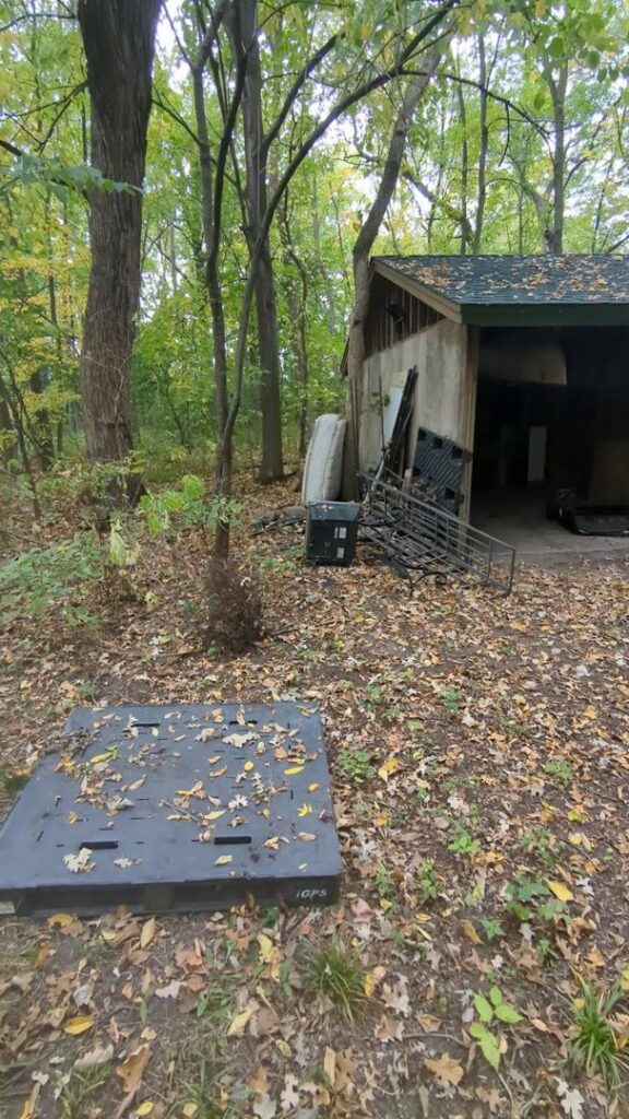 A pile of outdoor junk including a mattress and metal next to a shed for removal by Esule Services LLC - Anoka Junk Removal in Andover, MN.