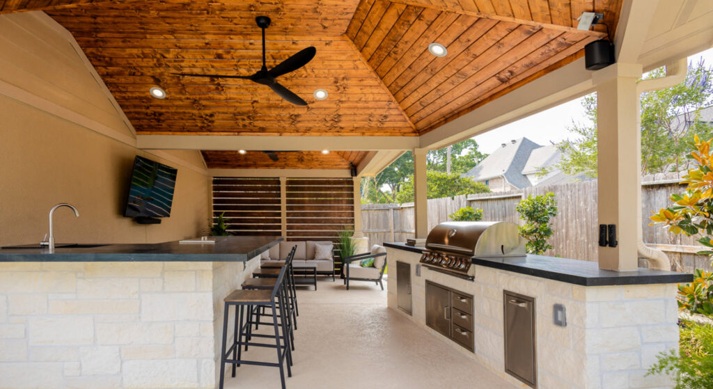 An outdoor kitchen and bar area under a covered patio by Houston Home Improvements & Construction in Houston, TX
