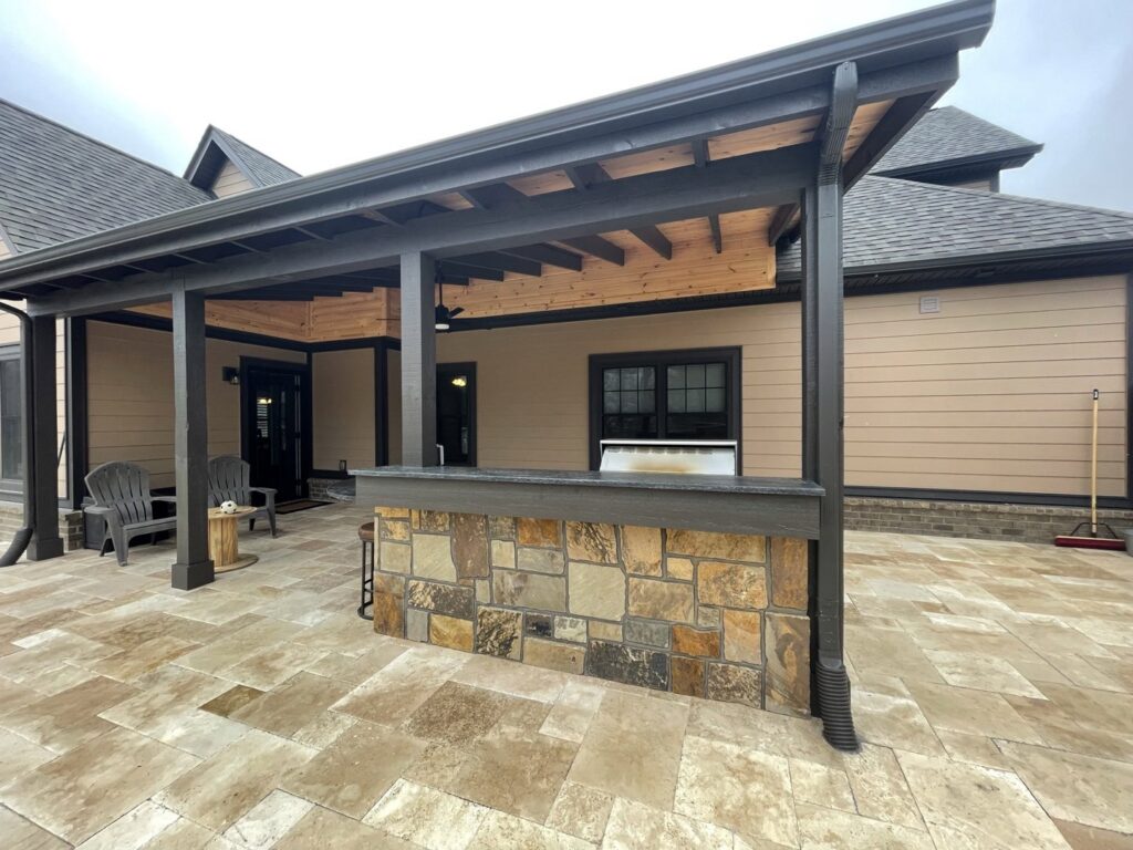 An elegant outdoor kitchen and bar area with a stone facade and a protective pergola by Technically Aesthetic General Contractors in Johnson City, TN.