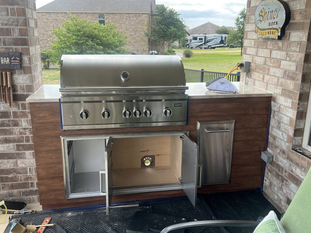 An outdoor kitchen featuring a built-in grill and a light-colored countertop, constructed by AAA Countertops in Austin, TX.