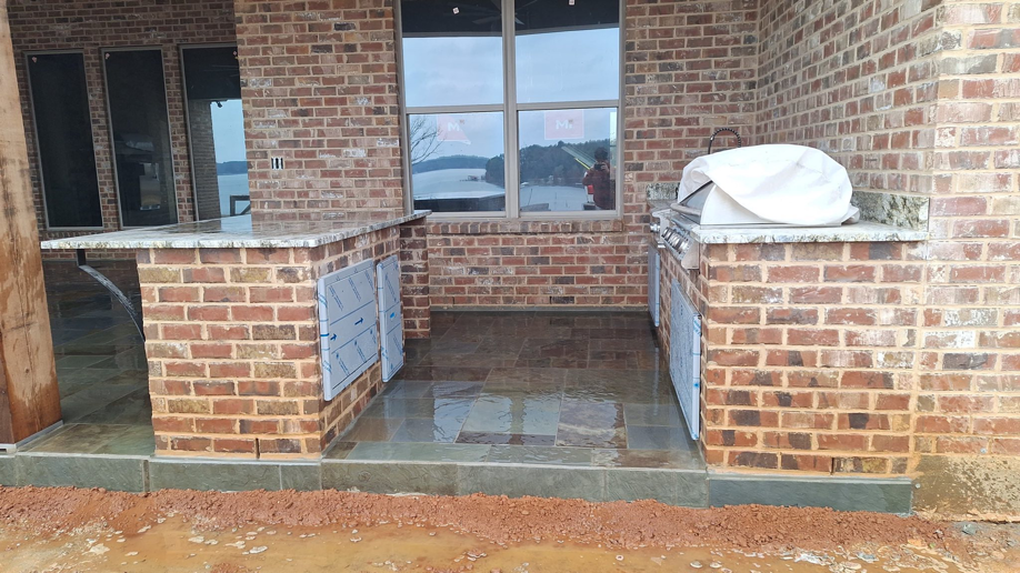 An outdoor kitchen under construction with brickwork, granite countertops, and a built-in grill by G W Dixon Construction Co, Inc in Calhoun, LA.