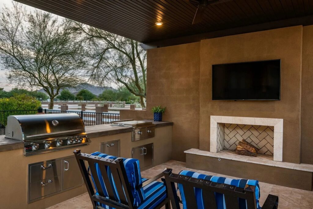 An outdoor kitchen and fireplace installation by Envy Pools in Gilbert, AZ.
