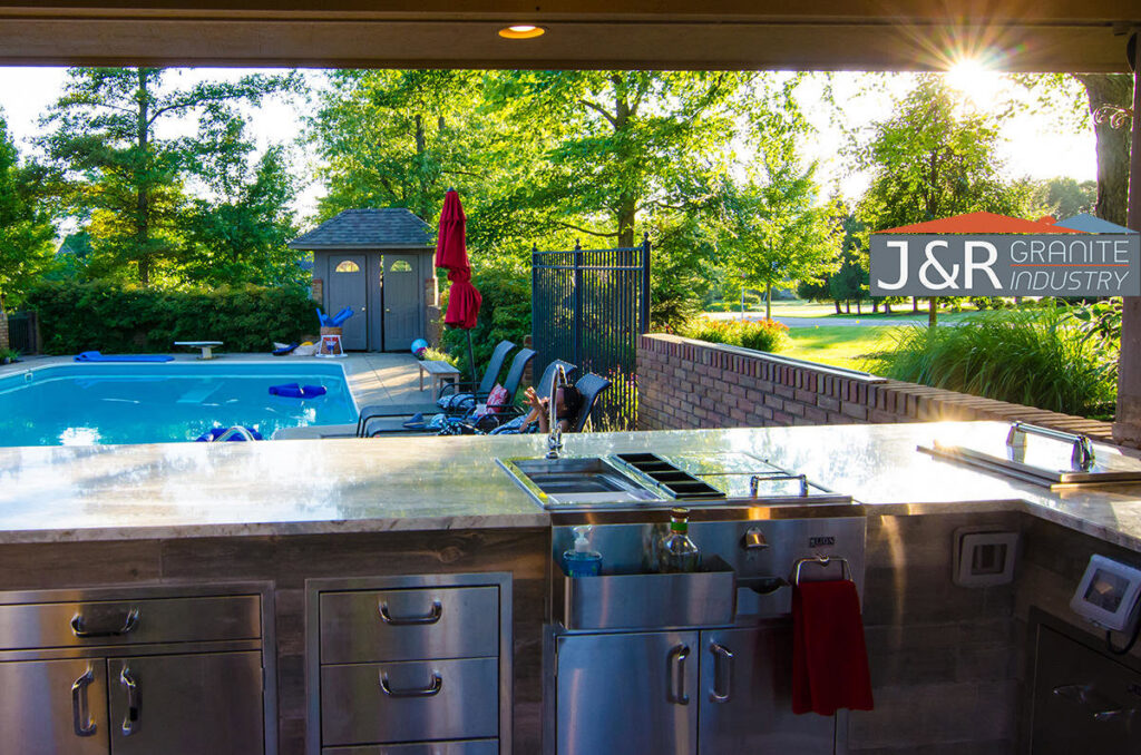 An outdoor kitchen featuring a built-in grill, sink, and granite countertops installed by J and R Granite Industry in Columbus, OH.