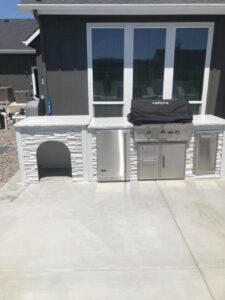 A custom outdoor kitchen with a built-in grill and refrigerator, constructed by The Huckleberry Handyman in Meridian, ID.