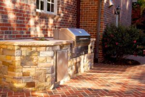 A custom outdoor kitchen and grill area with stone and brickwork by Rothrock Renovation & Remodeling in Winston-Salem, NC