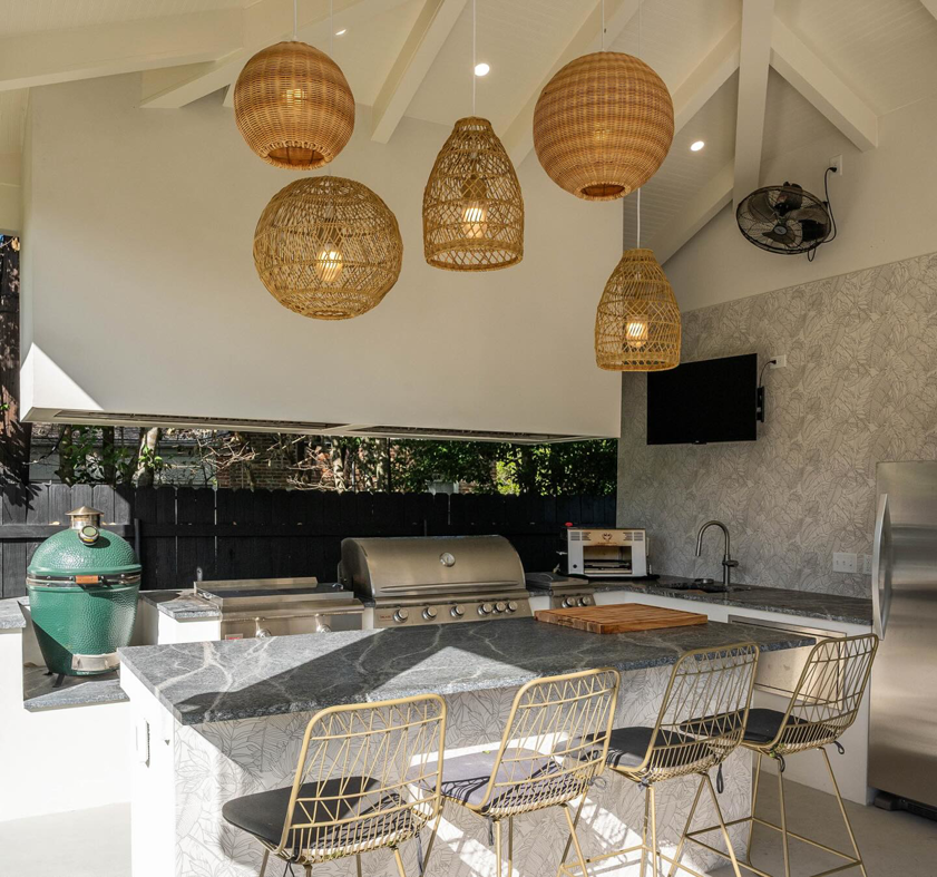 An outdoor kitchen with a built-in grill, sink, and stylish lighting installed by FITZ Construction in Kenner, LA.