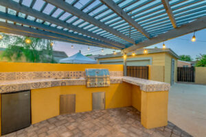 A newly built outdoor kitchen with a pergola, grill, and tiled countertops by Centennial Builders, LLC in Litchfield Park, AZ.