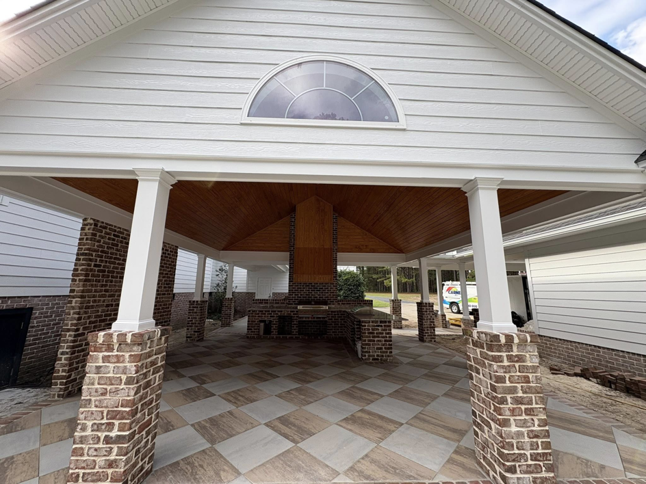 A newly constructed outdoor living area with brick pillars and a wooden ceiling by Carnelli Painting in Sumter, SC.