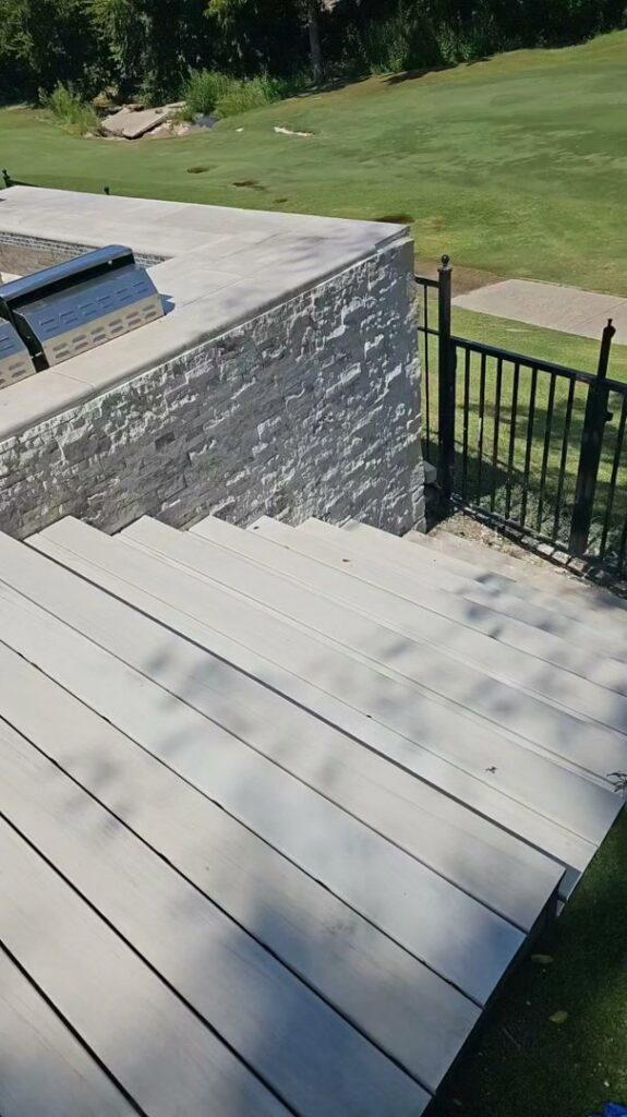 An outdoor living space featuring a stone wall, steps, and a built-in grill area by M.M. Remodelers in Resaca, GA.
