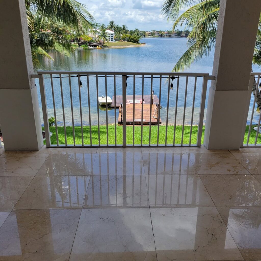 An outdoor balcony with expertly restored and polished marble tiles, overlooking a lake, by Cornerstone Services Management in Miami, FL.
