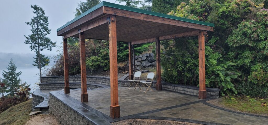 A newly constructed outdoor patio cover and stone retaining wall with steps by LMS Landscapes & Fence services in Auburn, WA.