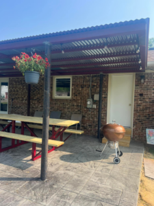 An outdoor metal patio cover with string lights installed over a stamped concrete area by Boyce Welding, LLC in Courtland, VA.