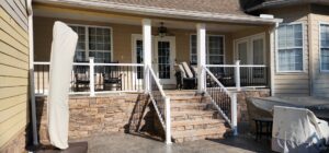A renovated outdoor patio and covered porch with stone facade and new railings by Rapid Repairs and Renovations in Knoxville, TN.
