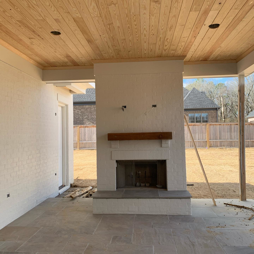 Outdoor patio with a newly constructed brick fireplace, wooden ceiling, and stone tile flooring by Mike Murphy Builders, LLC in Memphis, TN.
