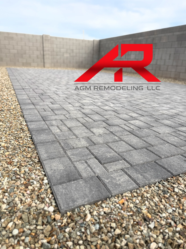 An outdoor patio featuring newly installed grey pavers surrounded by decorative gravel by AGM Remodeling LLC in Glendale, AZ.