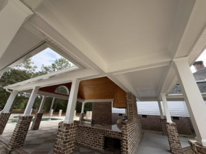 An outdoor patio with freshly painted white ceilings and pillars, overlooking a pool, by Carnelli Painting in Sumter, SC.