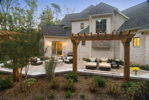 A beautiful outdoor patio with a wooden pergola and comfortable seating area by Rothrock Renovation & Remodeling in Winston-Salem, NC