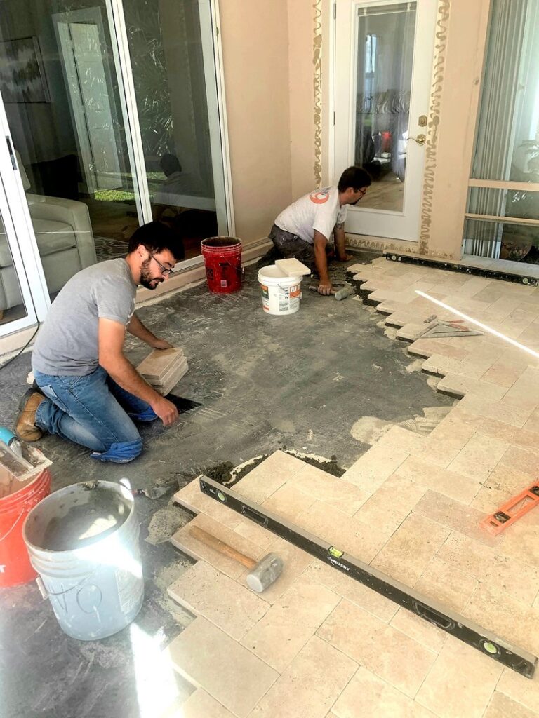 Two skilled workers from Stormtroopers Home Improvement installing large format tiles on an outdoor patio in Port St. Lucie, FL.