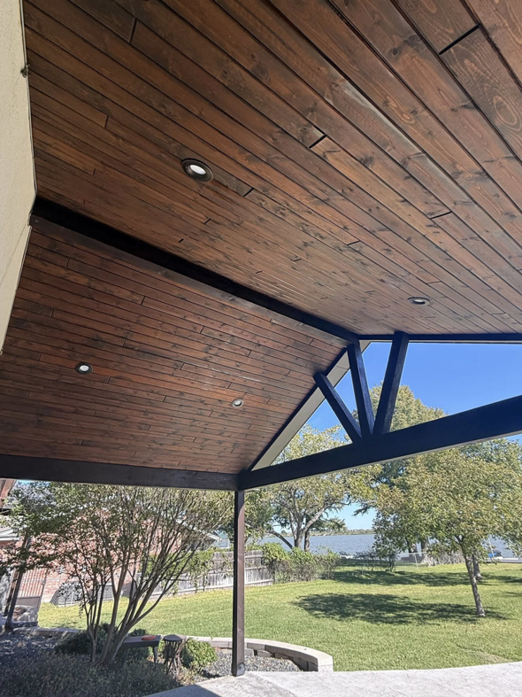 An outdoor patio with a finished wooden ceiling and recessed lights, offering a scenic lake view, completed by Javier's Painting in San Angelo, TX.