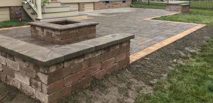 A newly installed outdoor paver patio with a built-in fire pit, a service offered by Huntington Home Repair in Huntington, WV.