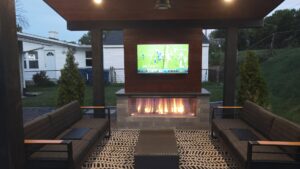 A custom outdoor pavilion with a built-in fireplace and mounted TV by Rescue Landscaping and Outdoor Living in St. Louis, MO