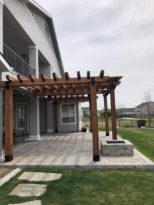 A newly constructed outdoor pergola and built-in fire pit on a paved patio by The Huckleberry Handyman in Meridian, ID.