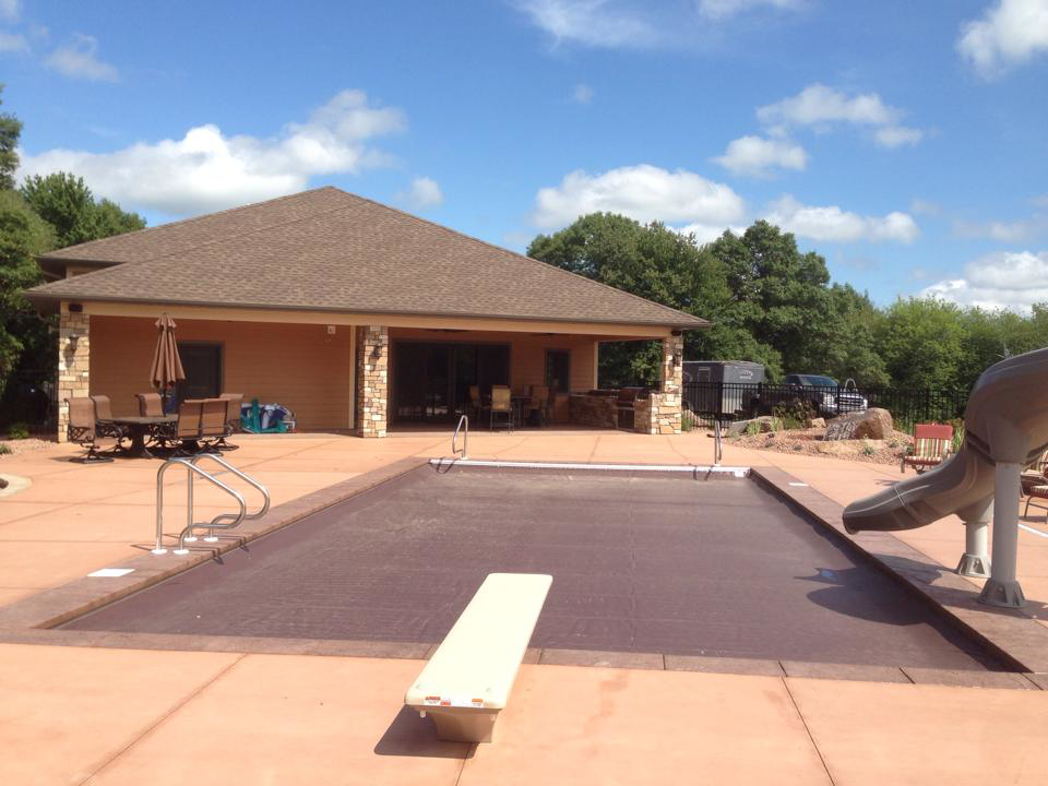 An inviting outdoor pool area with a covered patio and adjacent building by Ankeny Builders L.L.C. in Eau Claire, WI.