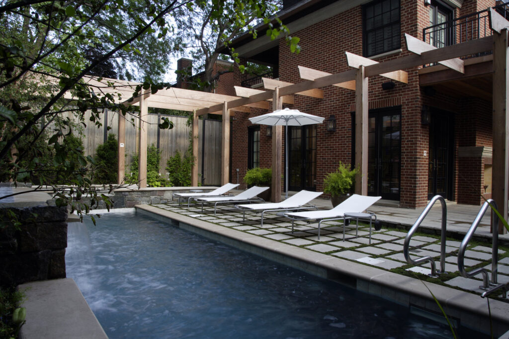An outdoor pool area with wooden pergolas and lounge chairs, designed by S.N. Peck Builder, Inc. in Chicago, IL.