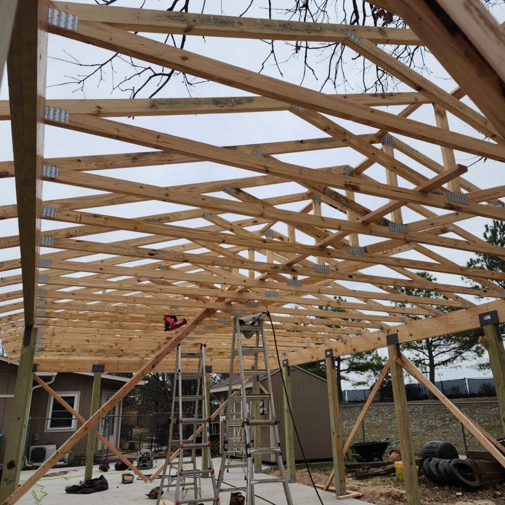 Construction of a wooden outdoor roof structure with ladders and tools by Holaway Custom Builds in Fayetteville, AR.