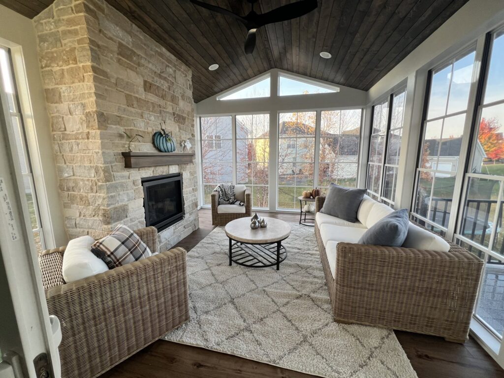An outdoor screened porch remodel with a stone fireplace and dark wood ceiling by J Brothers Design- Build- Remodel, Inc. in Corcoran, MN