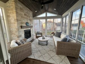 An outdoor screened porch remodel with a stone fireplace and dark wood ceiling by J Brothers Design- Build- Remodel, Inc. in Corcoran, MN